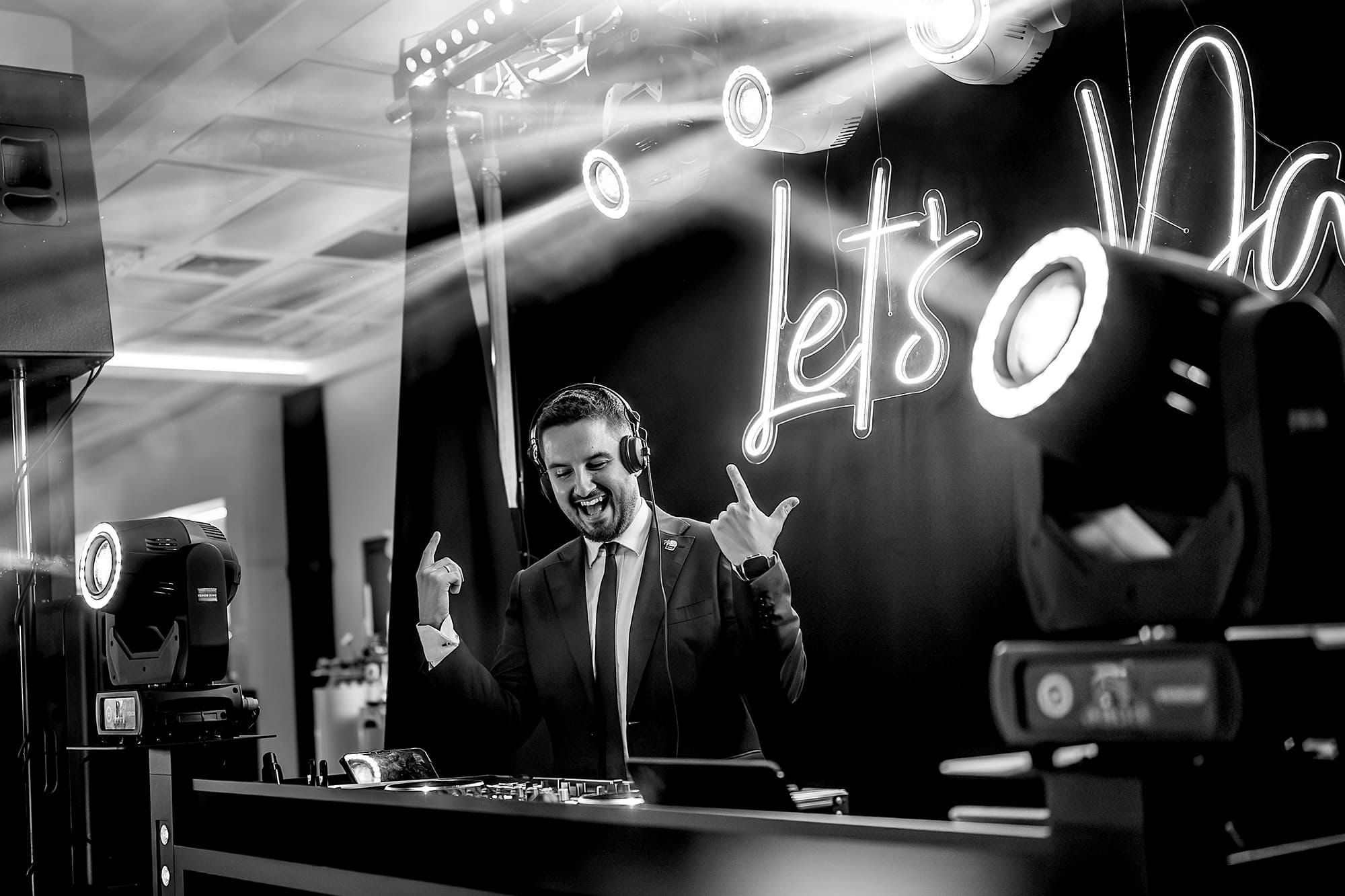 Kamil przy konsoli pod neonem Let’s Dance, czarno-białe