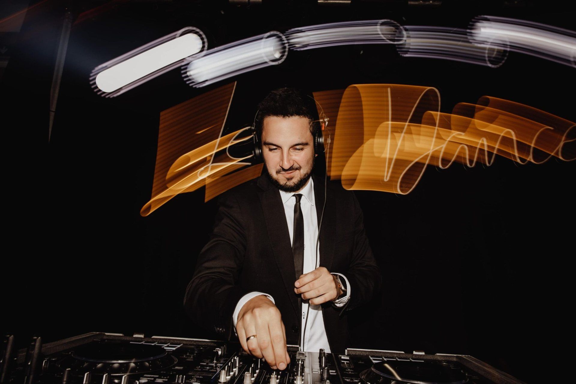 Kamil Spodniewski przy konsoli DJ, za nim złote smugi neonu Let’s Dance